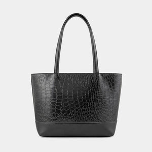 A black crocodile-embossed leather tote bag with dual top handles, shown against a plain light gray background.