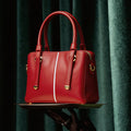 Red handbag held by a gloved hand against a dark curtain background