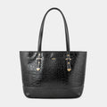A black crocodile-embossed leather tote bag with dual top handles and gold-tone hardware, centered on a light gray background.