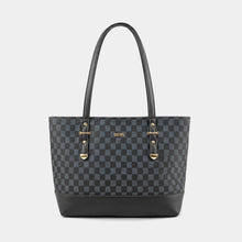 A black and dark gray checkered tote bag with black leather handles and base, featuring gold-tone hardware and a small gold 'GUESS' logo on the front, set against a light gray background.