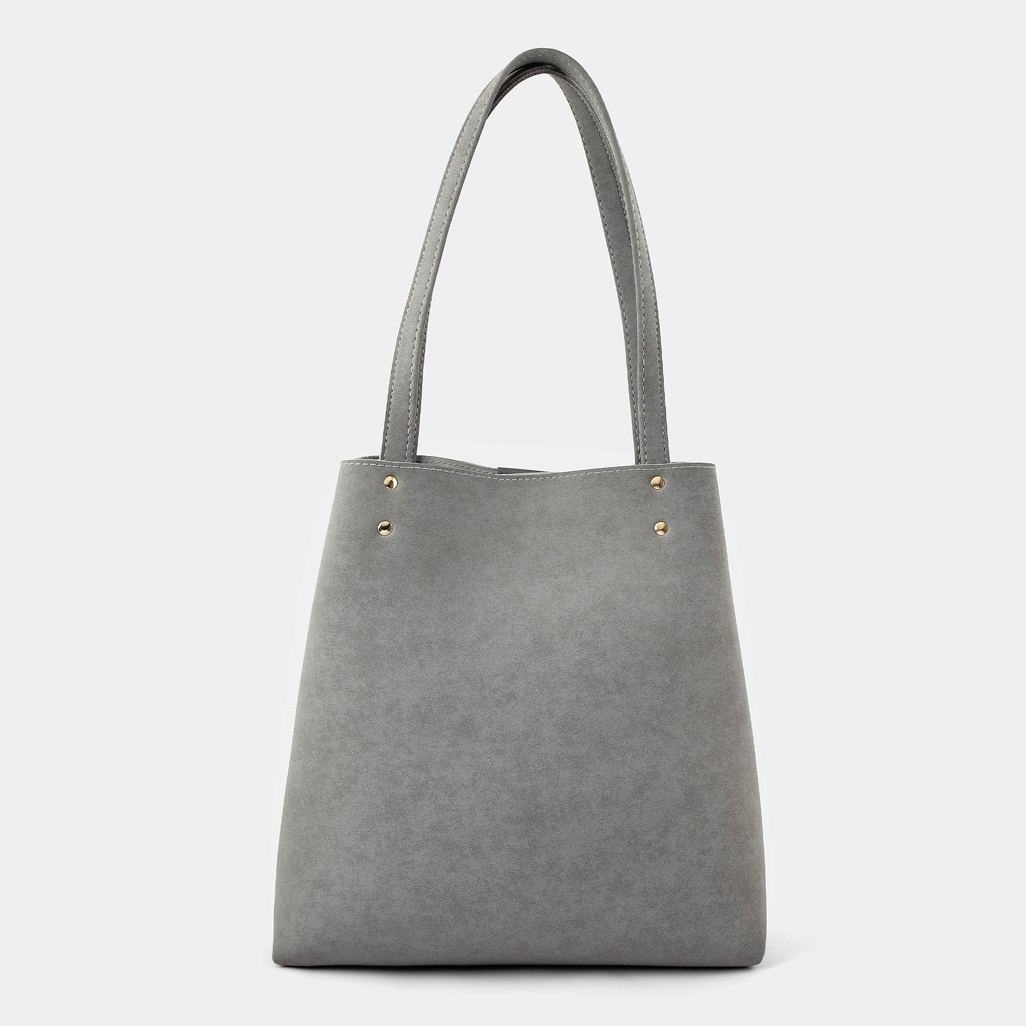 A gray faux-leather tote bag with double shoulder straps and small gold-tone metal rivets near the top, shown against a plain light gray background.