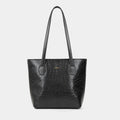 A black crocodile-embossed leather tote bag with dual shoulder straps and a small gold-tone logo plaque on the front, set against a solid light gray background.