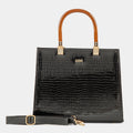 Black crocodile-patterned handbag with brown handle on a light gray background
